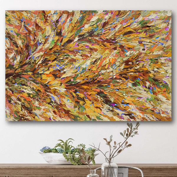 Abstract painting with warm colors on a wall above a wooden table.